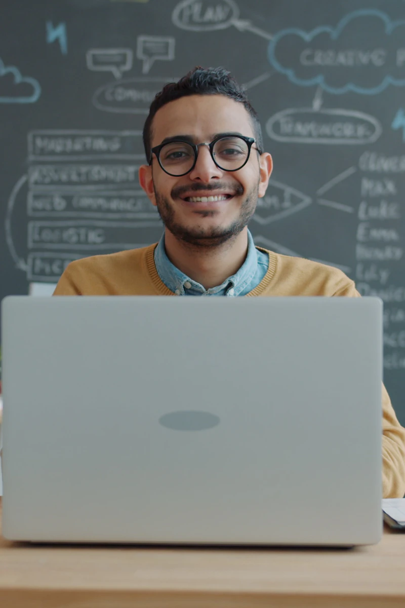 Profissional sorrindo em frente ao laptop em escritório moderno